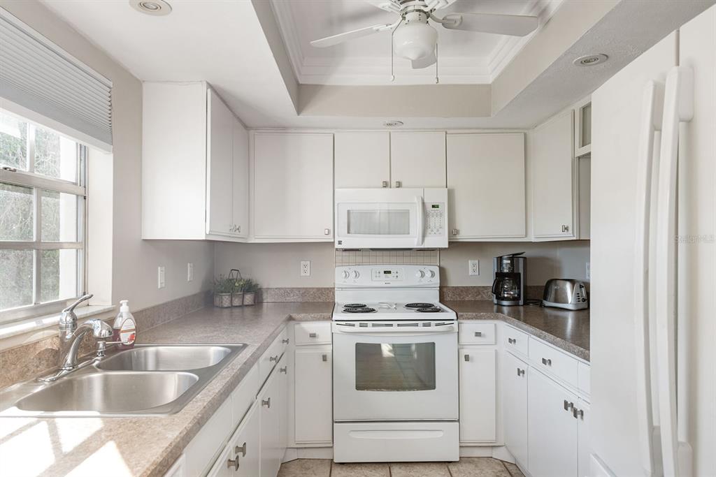1531 Placida Road, Unit 8101 Englewood, FL 34223 - Photo 33 of 76 a kitchen with granite countertop a sink stainless steel appliances white cabinets and a window