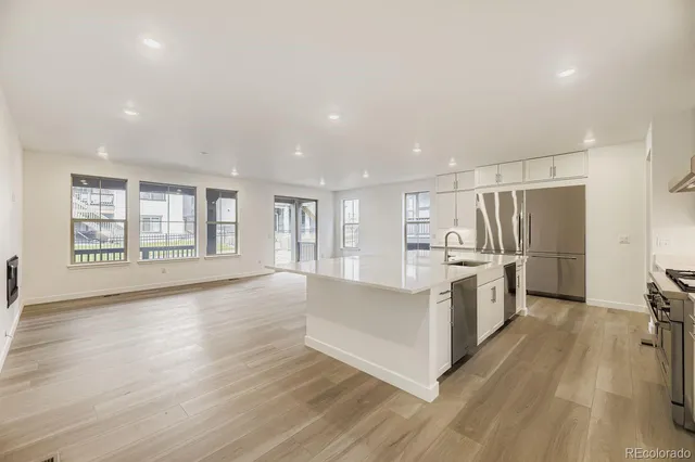 a large white kitchen with wooden floor and a window