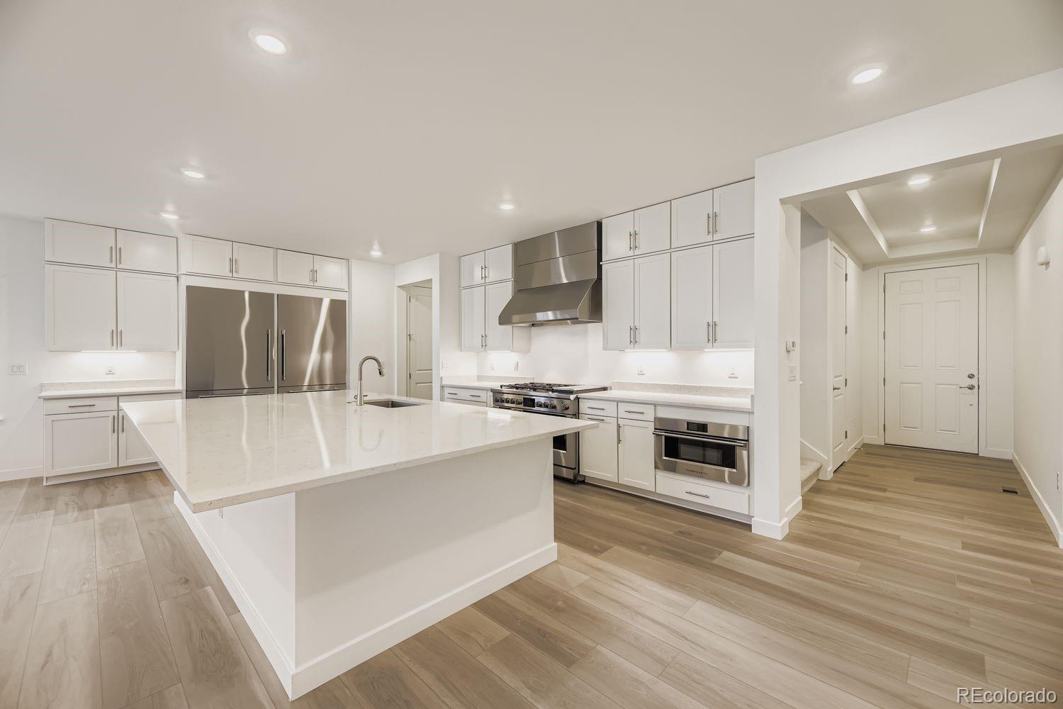 15596 West Beloit Avenue Morrison, CO 80465 - Photo 3 of 23 a large white kitchen with a stove a sink dishwasher and a refrigerator with wooden floor