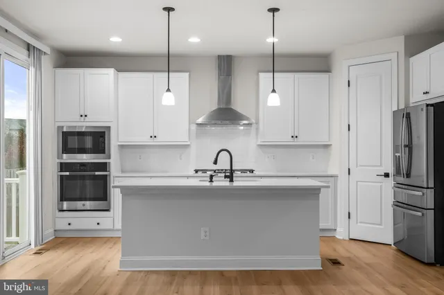 a kitchen with stainless steel appliances granite countertop a refrigerator a sink and white cabinets
