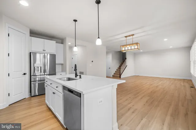 a room with kitchen island a sink and wooden floor