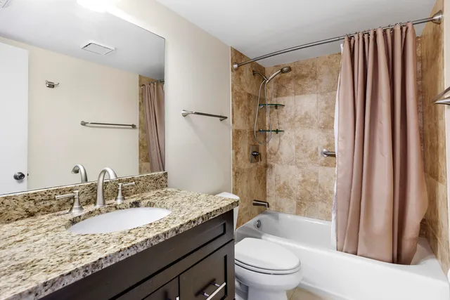 a bathroom with a granite countertop sink toilet and shower