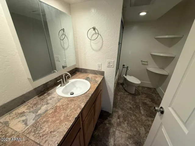 a bathroom with a granite countertop sink a toilet and a mirror