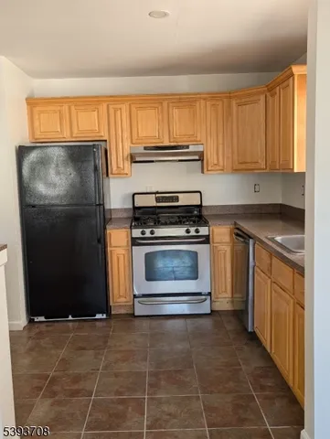 a kitchen with granite countertop a stove a sink and a refrigerator