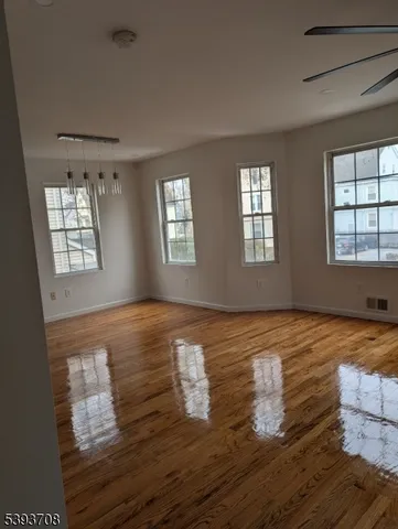 a view of an empty room with window and wooden floor