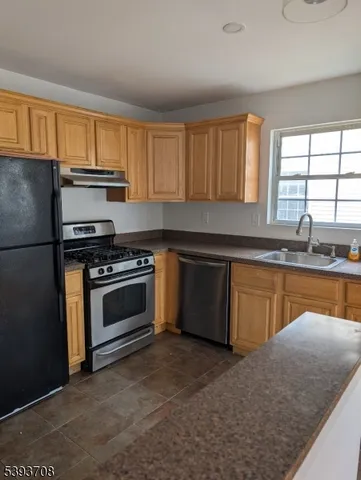 a kitchen with granite countertop a sink cabinets stainless steel appliances and a window