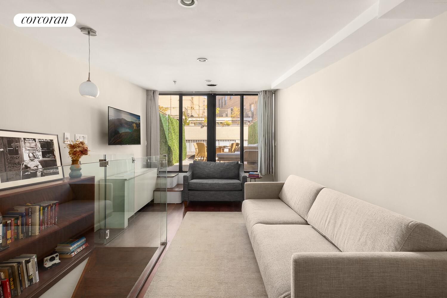 67 East 11th Street, Unit 705 Manhattan, NY 10003 - Photo 4 of 10 a living room with furniture and a flat screen tv