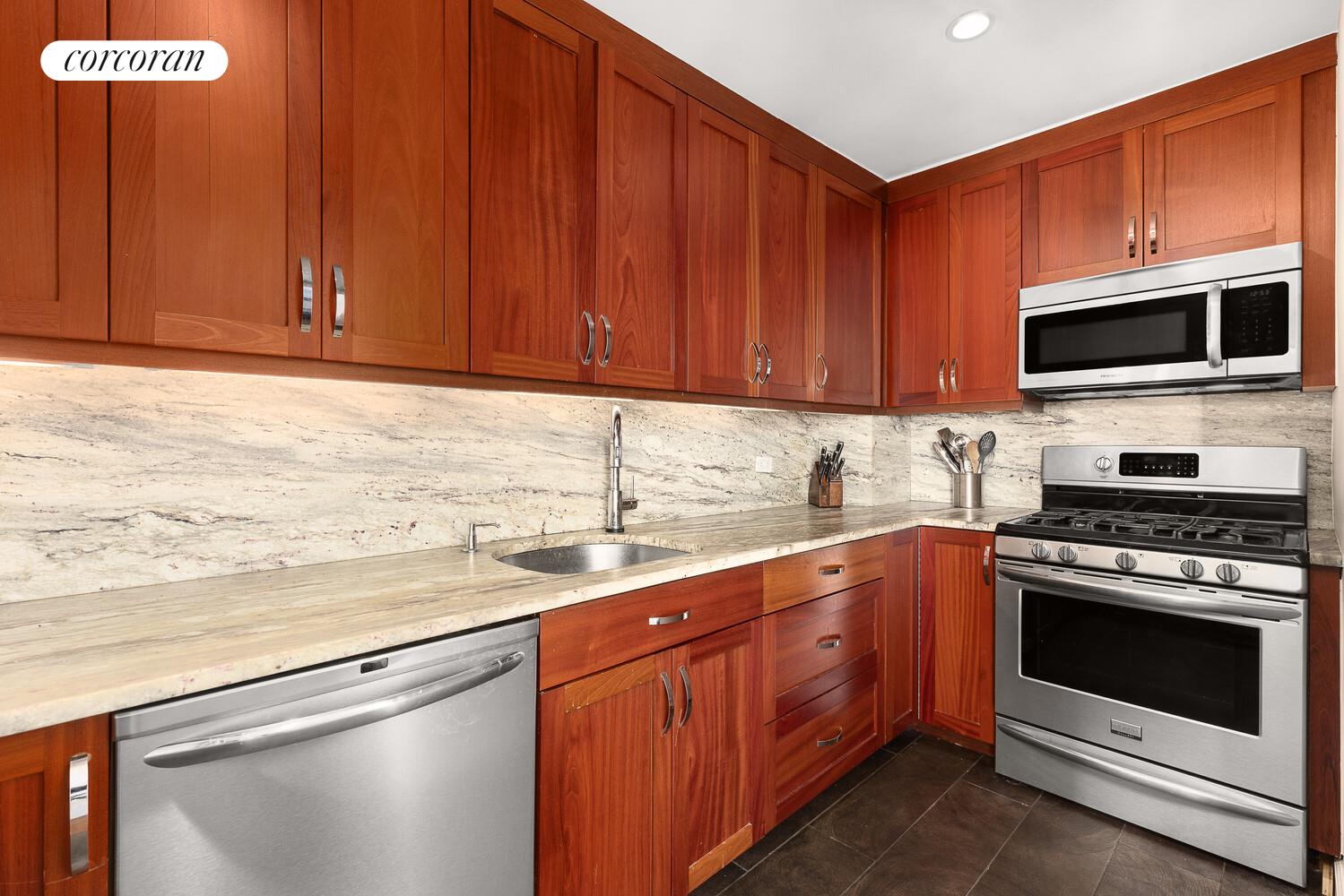 67 East 11th Street, Unit 705 Manhattan, NY 10003 - Photo 5 of 10 a kitchen with stainless steel appliances granite countertop a sink a stove and a microwave