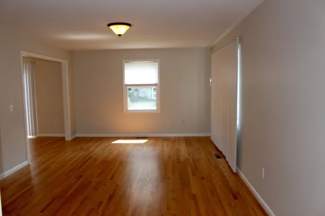 a view of an empty room with wooden floor and a window