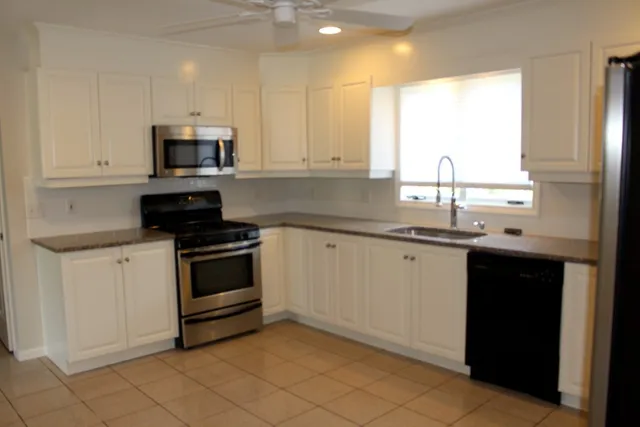 a kitchen with stainless steel appliances granite countertop white cabinets a sink and a window