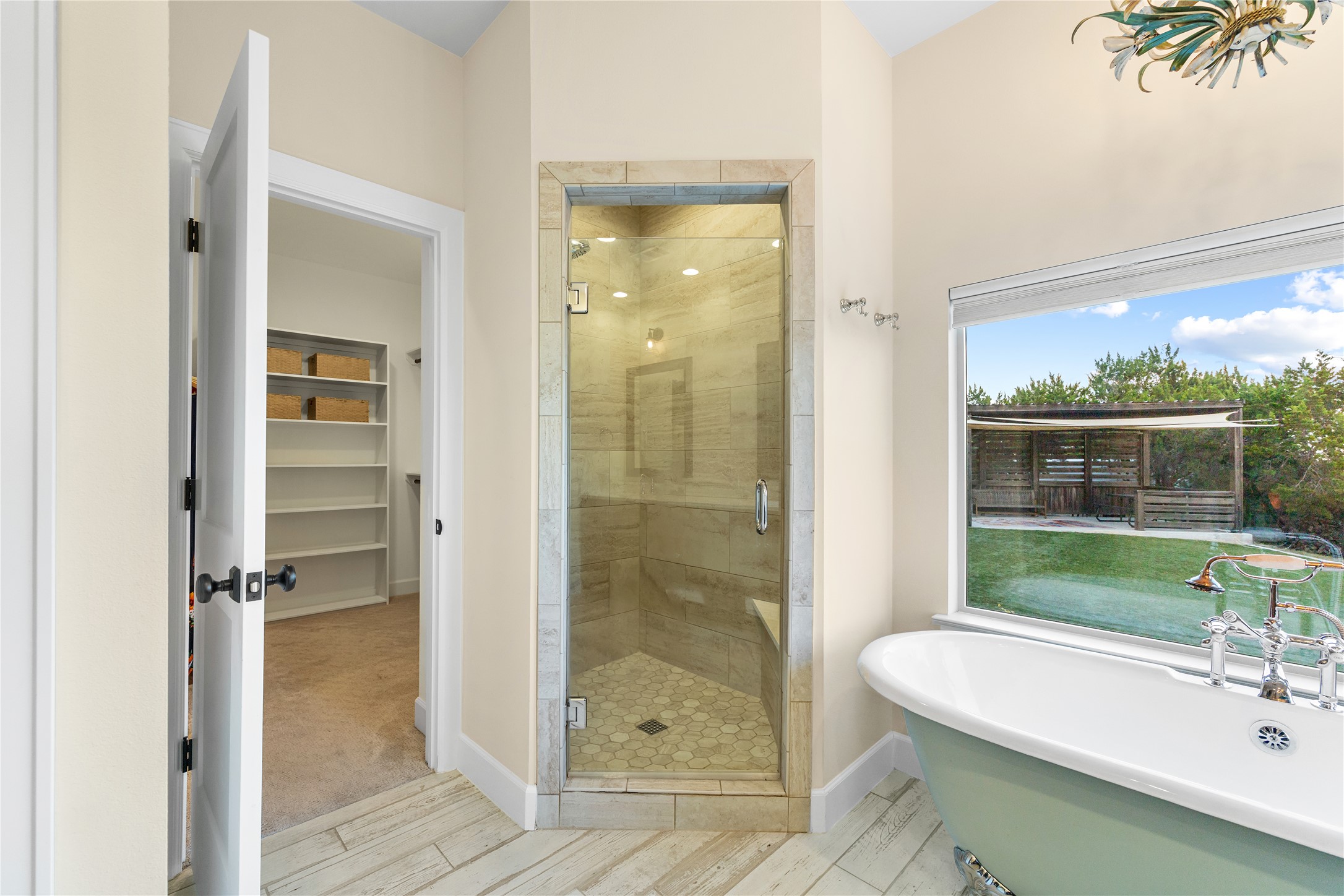 1017 Westland Ridge Road Dripping Springs, TX 78620 - Photo 14 of 40 A glass-enclosed walk-in shower and freestanding tub complement wood-look tile flooring.