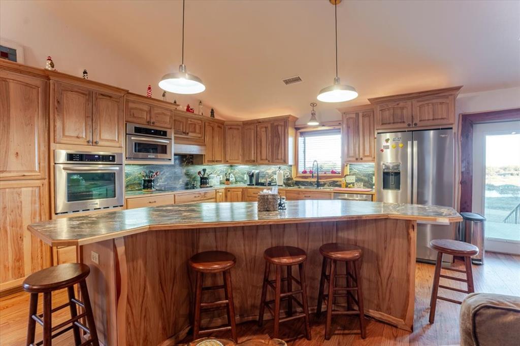 2117 Highway 6 Cisco, TX 76437 - Photo 11 of 35 a kitchen with kitchen island granite countertop a table chairs microwave and cabinets
