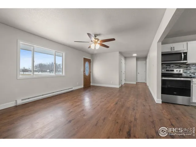 a view of an empty room with a kitchen and wooden floor