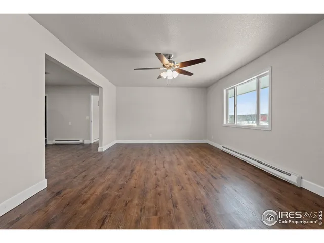 a view of an empty room with a window and wooden floor