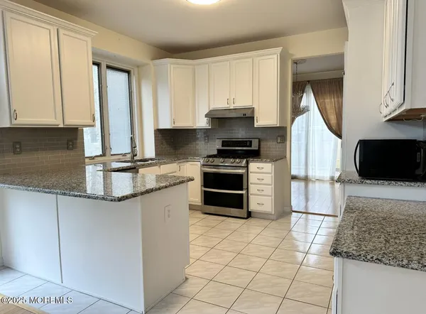 a kitchen with stainless steel appliances granite countertop a stove a sink and a microwave