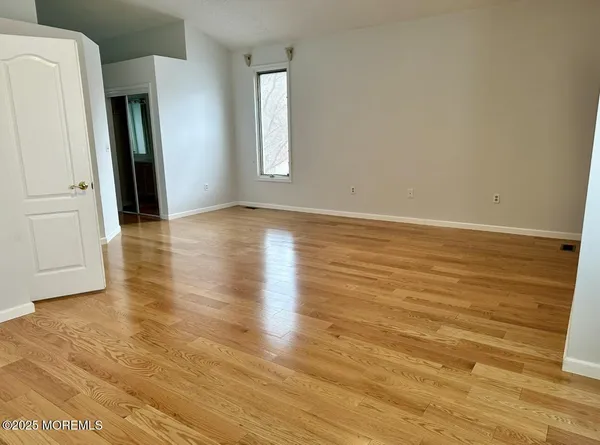 a view of an empty room with window and wooden floor
