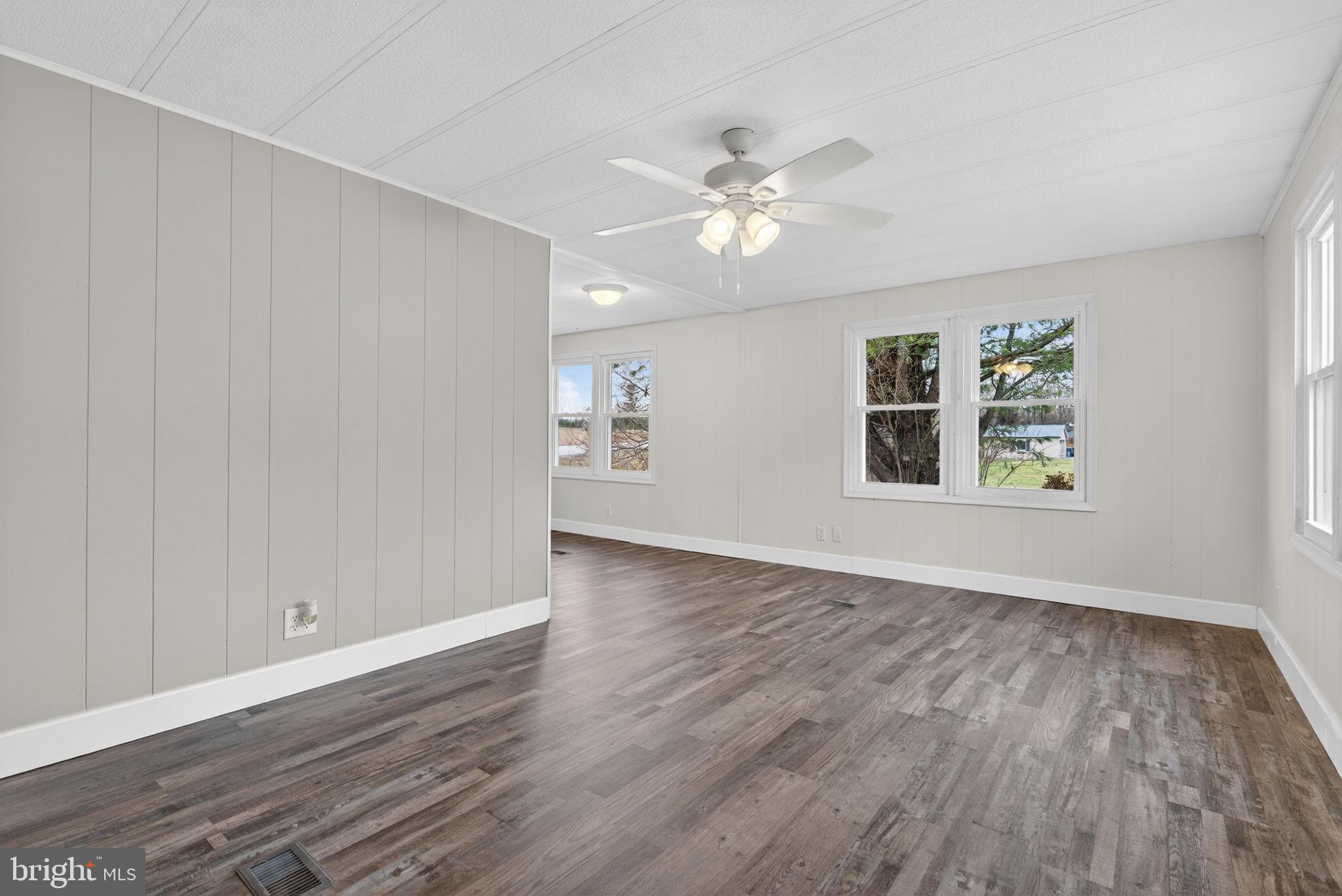 4918 Pleasant Valley Road York, PA 17406 - Photo 4 of 30 an empty room with wooden floor chandelier fan and windows