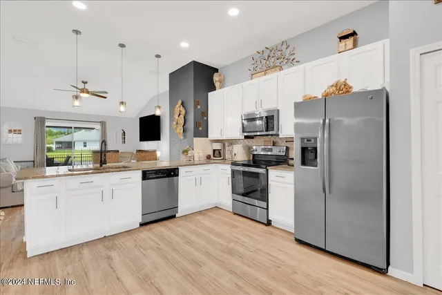 a kitchen with stainless steel appliances kitchen island granite countertop a refrigerator a stove and a wooden floors