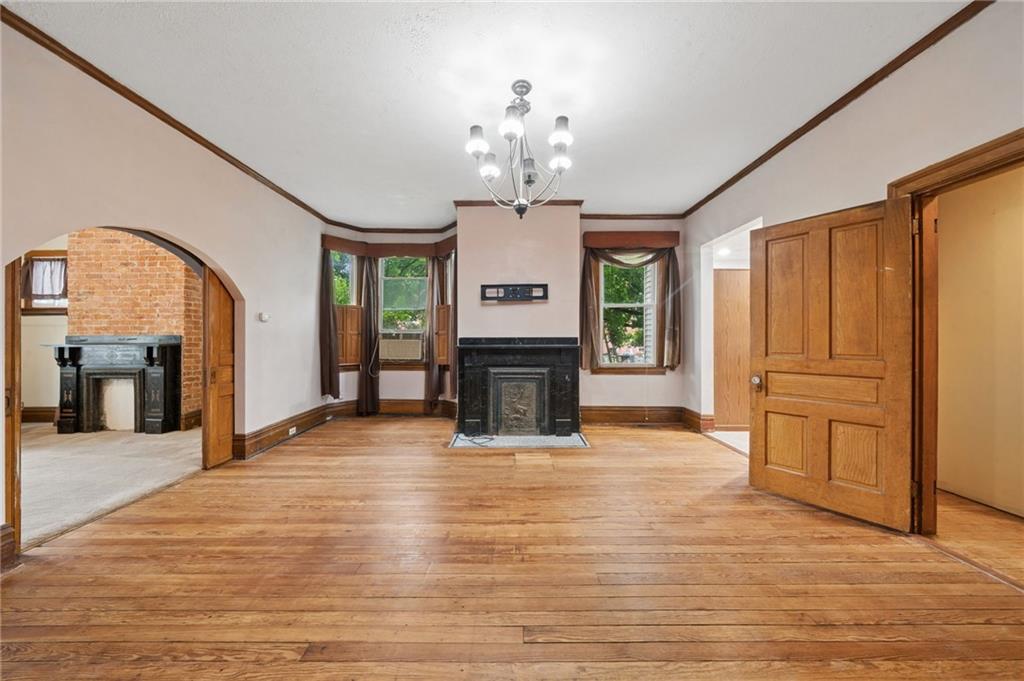 1523 Evergreen Road Pittsburgh, PA 15209 - Photo 6 of 35 a view of an empty room with a fireplace a chandelier and wooden floor