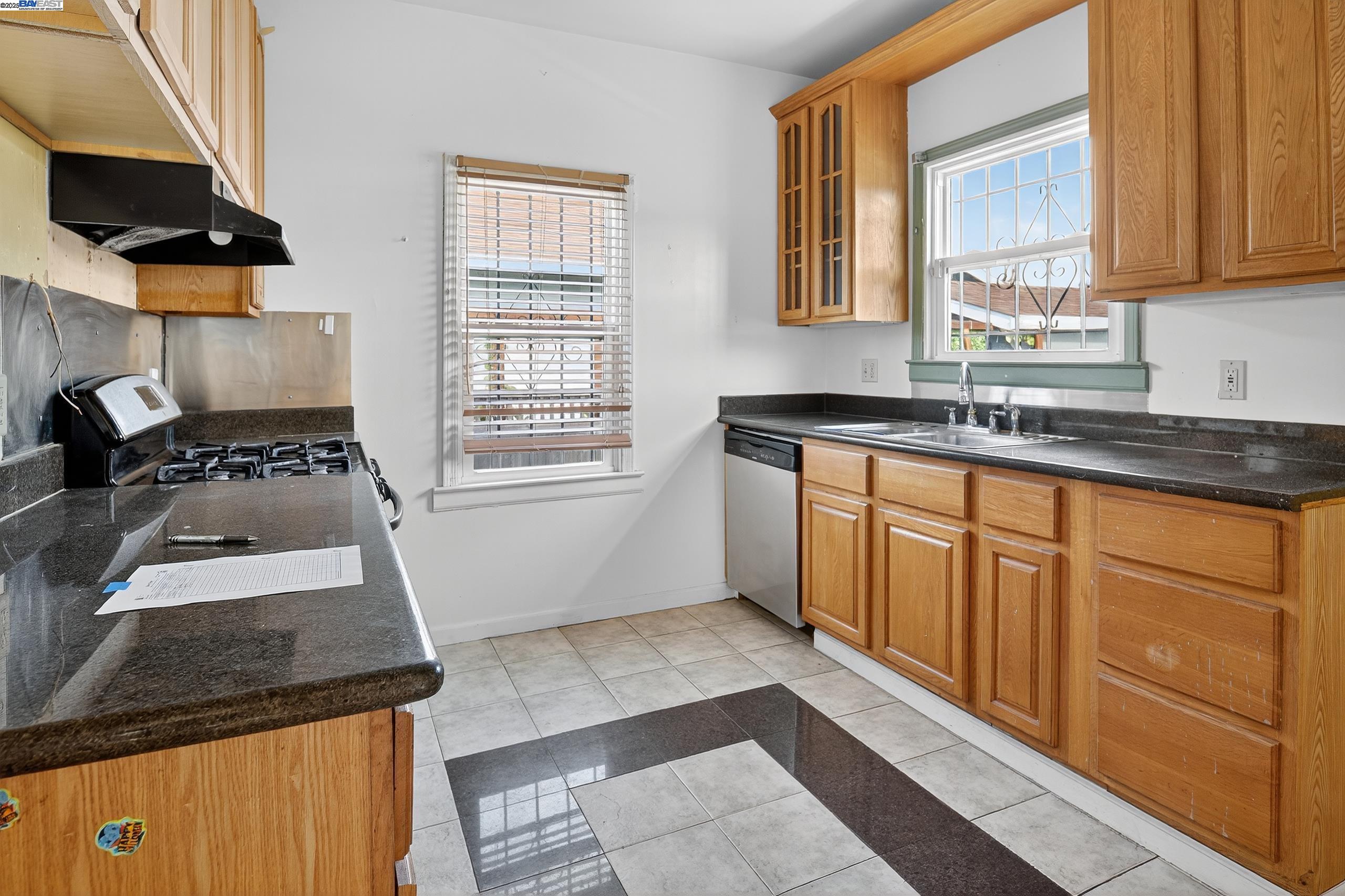 7412 Weld Street Oakland, CA 94621 - Photo 6 of 19 a kitchen with granite countertop stainless steel appliances a stove a sink and a microwave