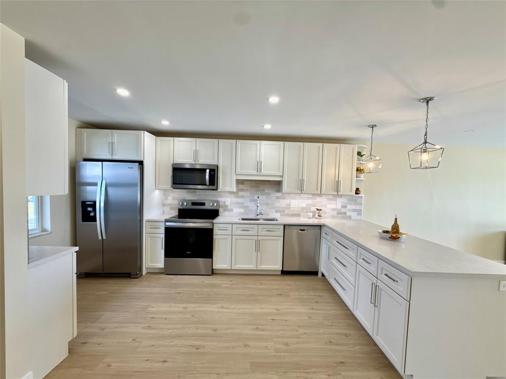 a large kitchen with stainless steel appliances kitchen island granite countertop a refrigerator and a stove top oven