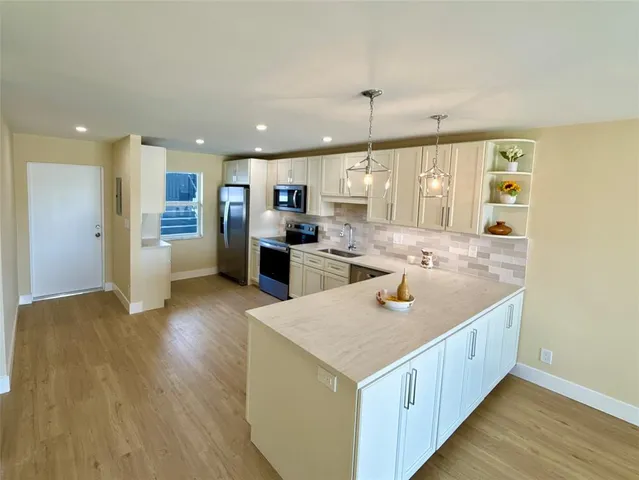 a kitchen with stainless steel appliances granite countertop a sink a stove and a wooden floors