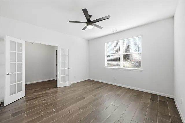 an empty room with wooden floor and ceiling fan