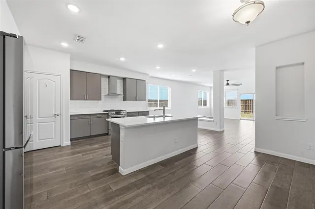 a large kitchen with stainless steel appliances a large counter top a stove and a refrigerator