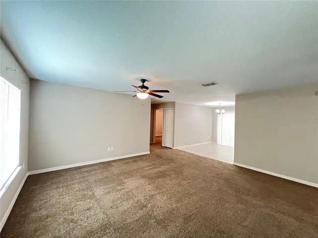 an empty room with windows and a ceiling fan