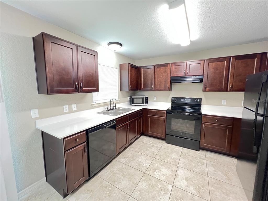 2427 Southwest 168th Loop Ocala, FL 34473 - Photo 10 of 21 a kitchen with a stove a sink a microwave and wooden cabinets