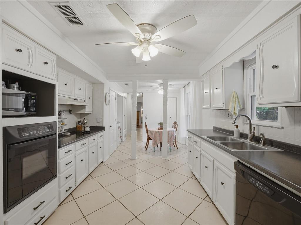 907 4th Street Graham, TX 76450 - Photo 10 of 34 a large white kitchen with granite countertop a sink white cabinets and stainless steel appliances