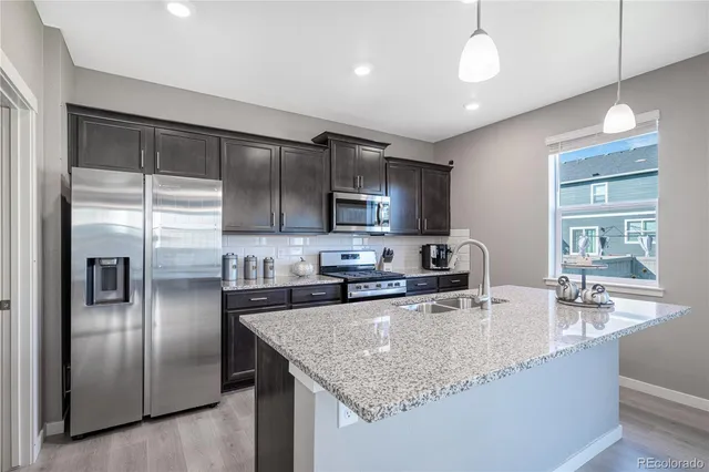 a kitchen with stainless steel appliances granite countertop a sink a stove and a refrigerator