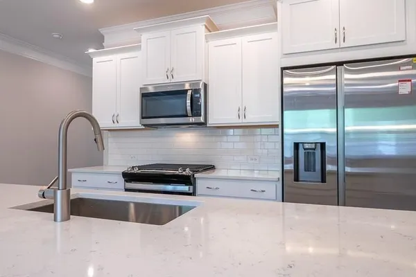a kitchen with granite countertop a refrigerator and a stove top oven