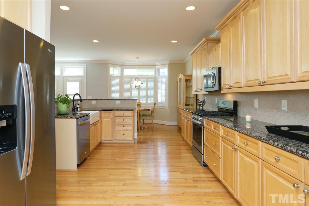 1164 Harp Street Raleigh, NC 27604 - Photo 7 of 25 a large kitchen with stainless steel appliances a large counter top a stove a refrigerator and cabinets