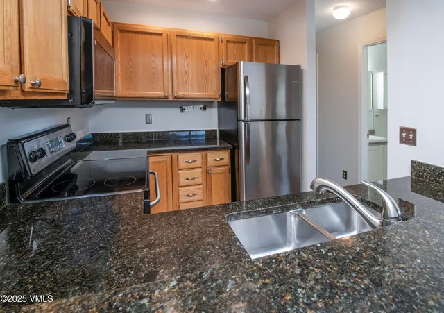 a kitchen with stainless steel appliances granite countertop a sink a refrigerator and a sink