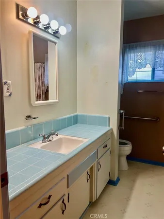 a bathroom with a granite countertop sink a toilet and a mirror