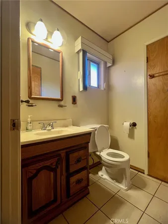 an empty room with chandelier fan and kitchen view