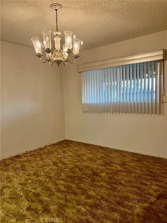 a view of a refrigerator in kitchen and an empty room with wooden floor