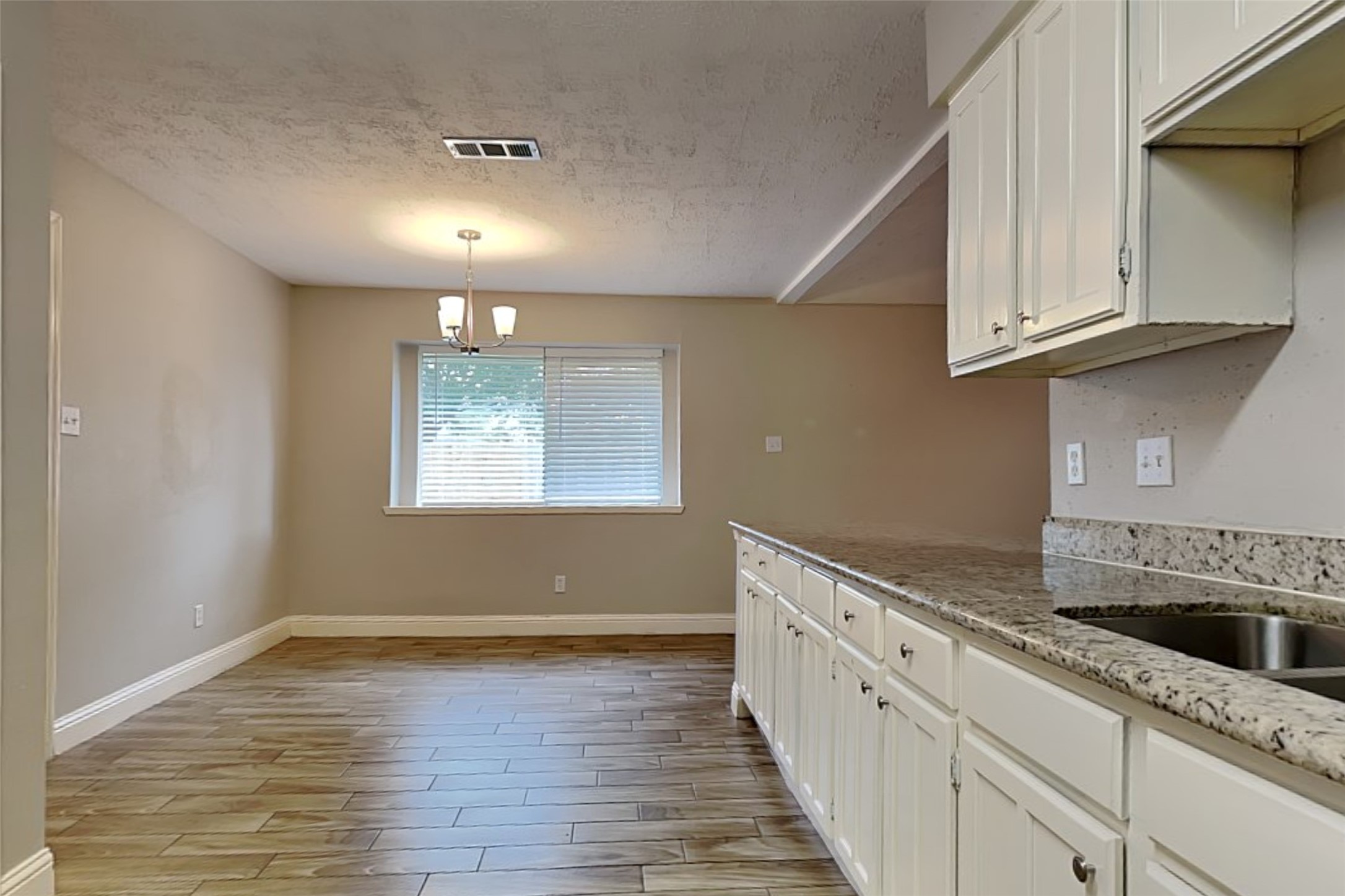 19902 Pinefield Court Humble, TX 77338 - Photo 9 of 23 a kitchen with granite countertop white cabinets and a wooden floor