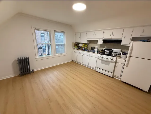 a kitchen with granite countertop a stove a sink dishwasher and a refrigerator with wooden floor