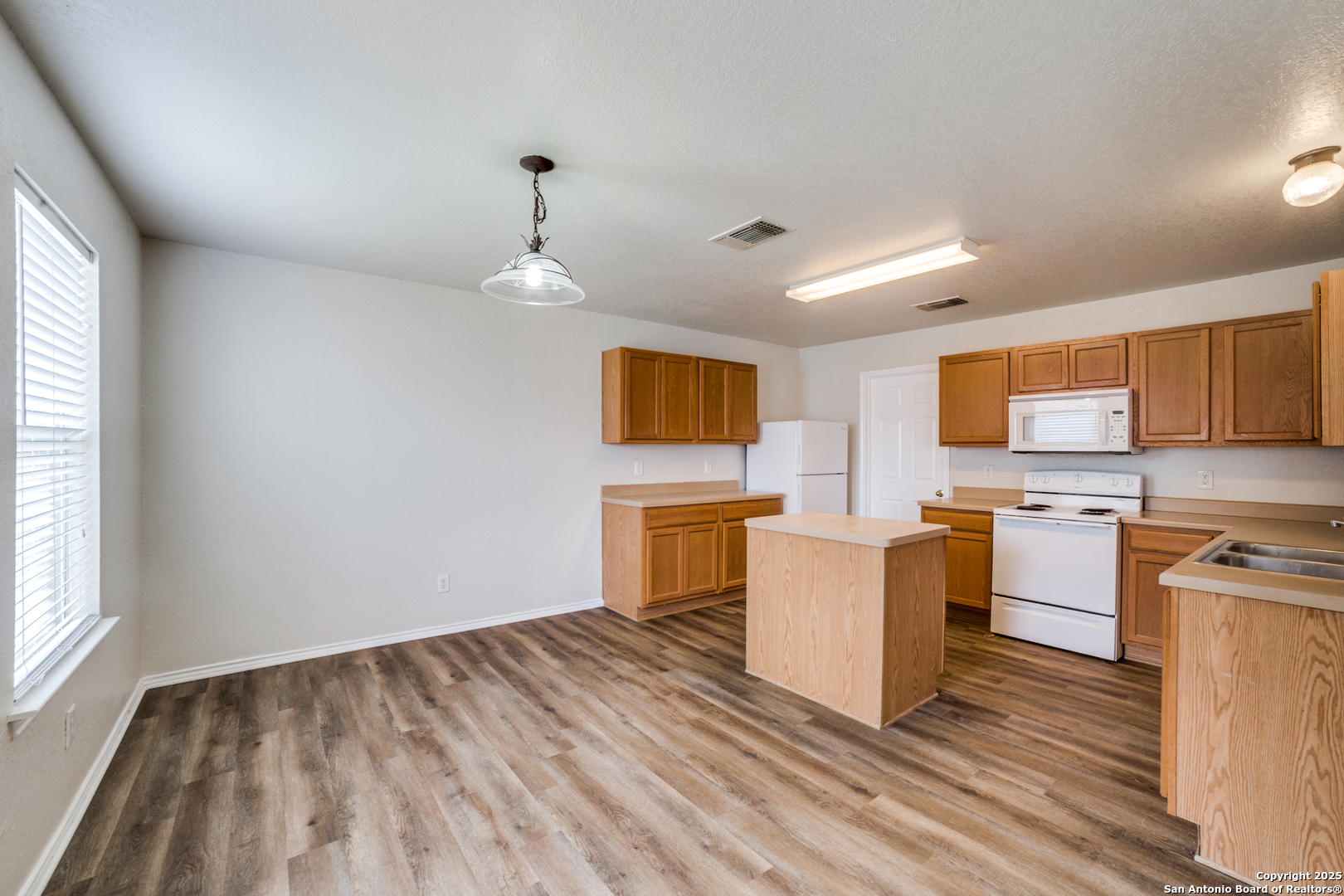 5616 Poppy Seed Run Leon Valley, TX 78238 - Photo 22 of 42 a kitchen with stainless steel appliances granite countertop a stove top oven a sink dishwasher a dining table and chairs with wooden floor