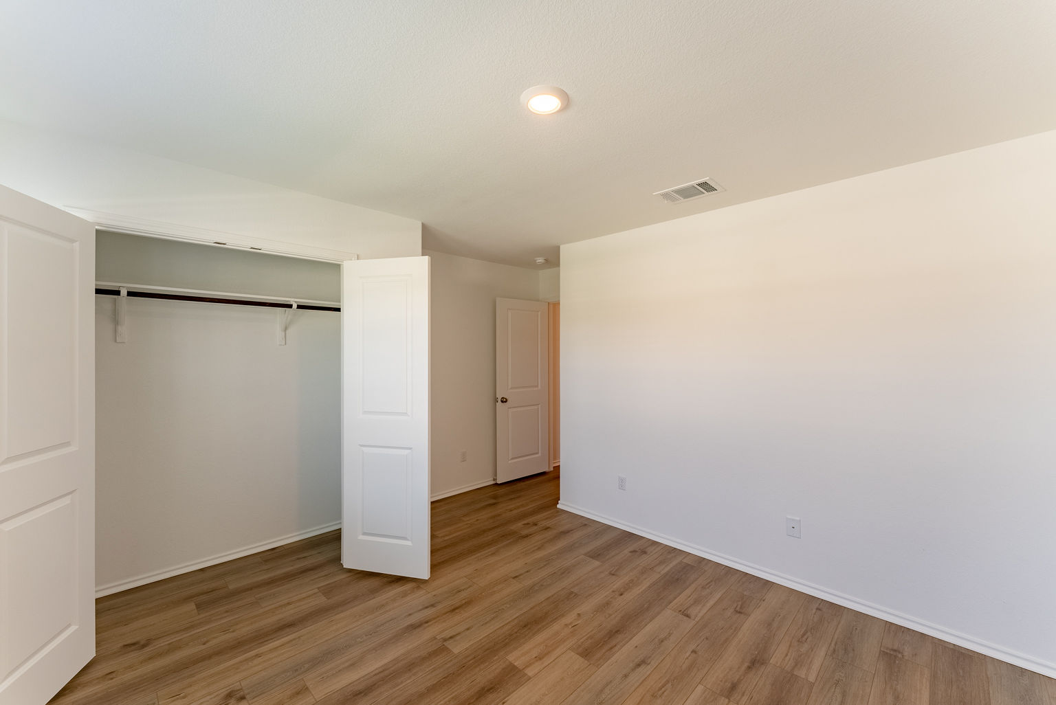 137 River Rise Road Kyle, TX 78640 - Photo 20 of 26 Unfurnished bedroom with a barn door, light wood finished floors, a closet, and recessed lighting