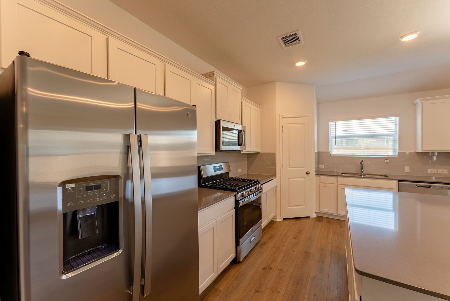 137 River Rise Road Kyle, TX 78640 - Photo 7 of 26 Kitchen with stainless steel appliances, white cabinetry, light wood-type flooring, tasteful backsplash, and recessed lighting
