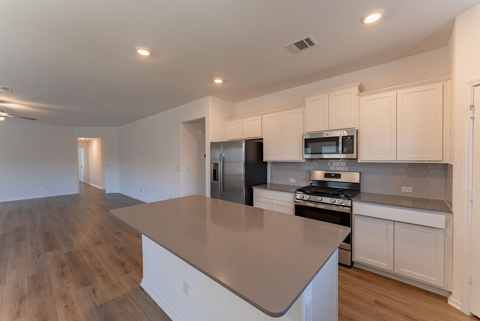 137 River Rise Road Kyle, TX 78640 - Photo 8 of 26 Kitchen featuring stainless steel appliances, decorative backsplash, light wood-type flooring, a center island, and white cabinetry