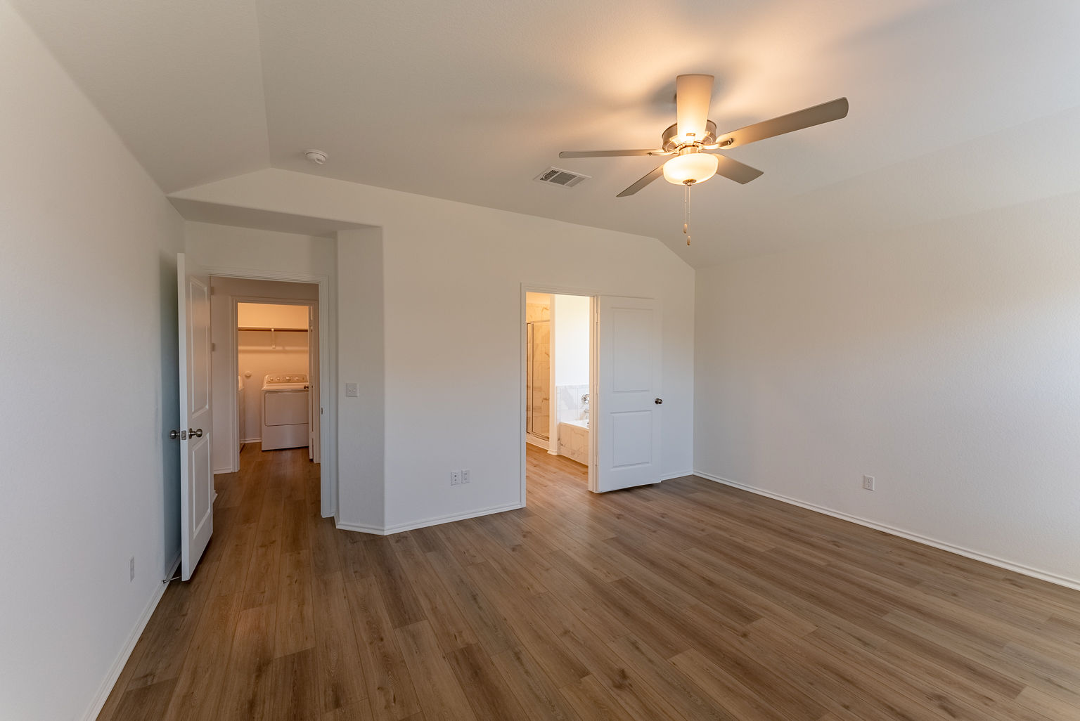 137 River Rise Road Kyle, TX 78640 - Photo 10 of 26 Unfurnished bedroom featuring vaulted ceiling, ceiling fan, wood finished floors, and ensuite bathroom