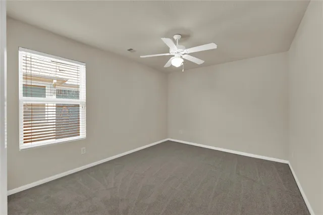 an empty room with a window and a fan