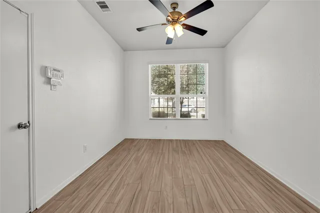 a view of empty room with wooden floor and fan