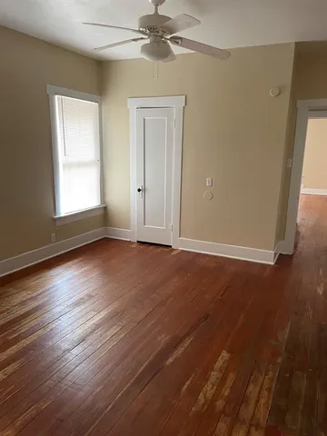 an empty room with wooden floor fan and windows