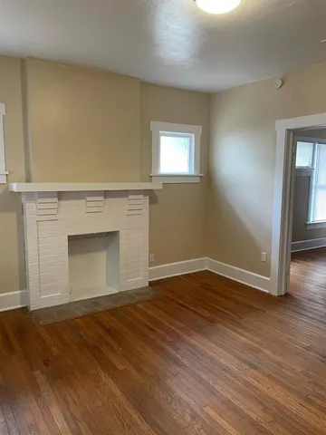 a view of empty room with wooden floor and fireplace