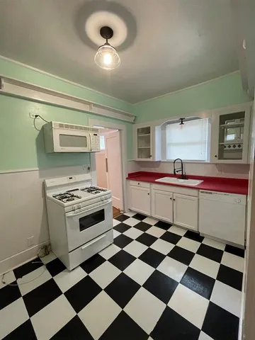 a kitchen with a checkered floor and white cabinets